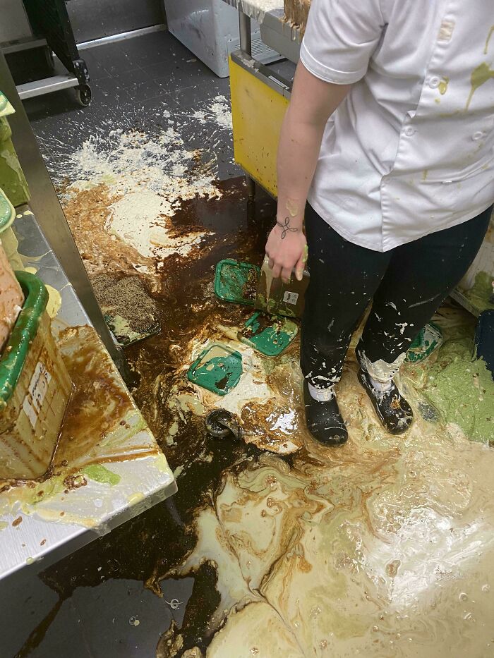 Food service worker in a messy kitchen with spilled sauces on the floor, highlighting challenges in the industry.