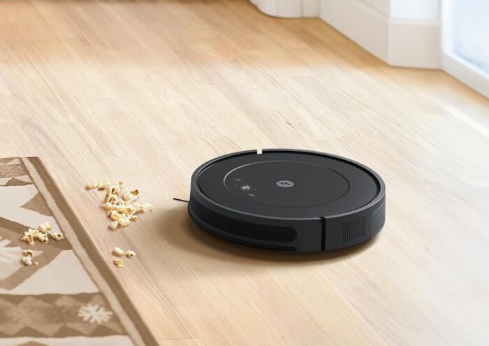 Robot vacuum on a wood floor cleaning popcorn pieces, illustrating impulse buys worth it.