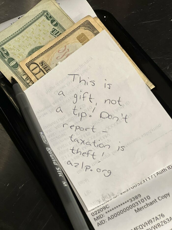 Note with cash on a restaurant tray, message discussing taxation in the food service industry.