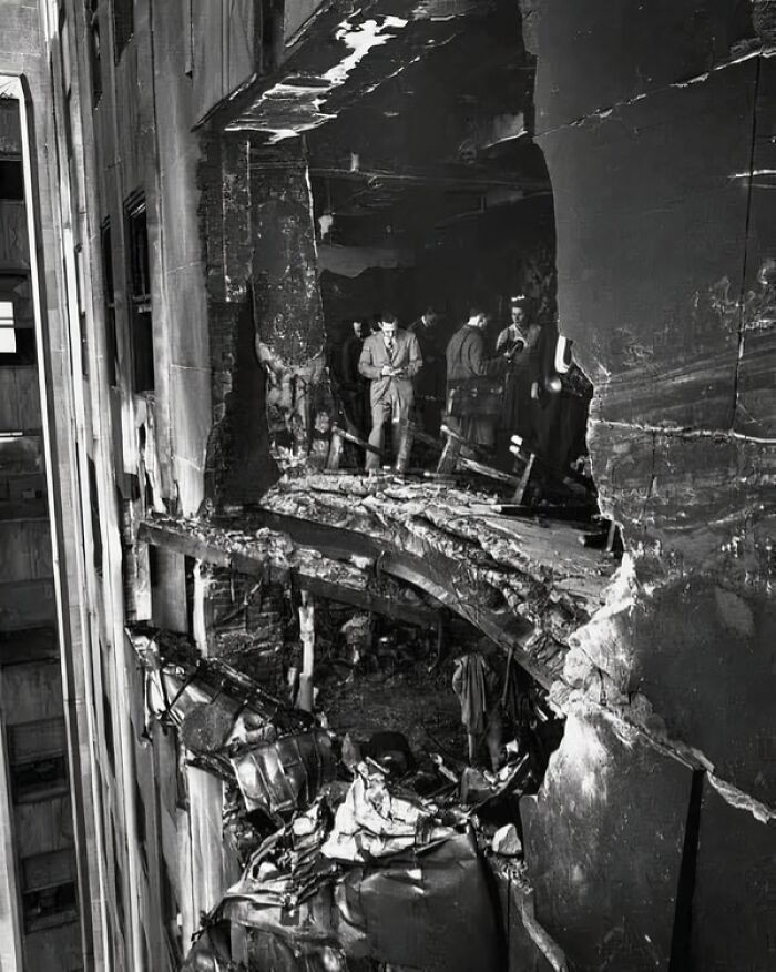 Historic event aftermath showing damaged building facade with rubble and people inspecting the scene.