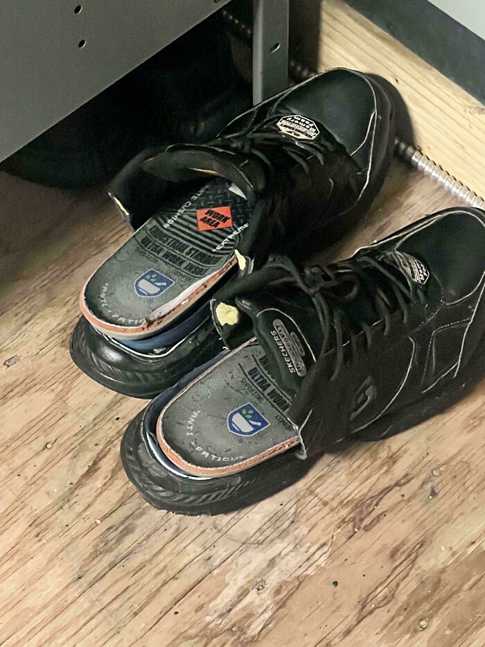 Black work shoes on a wooden floor, representative of daily life in the food service industry.