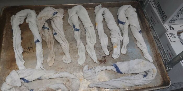 Dirty kitchen towels twisted on a metal tray, illustrating a typical scene from the food service industry.