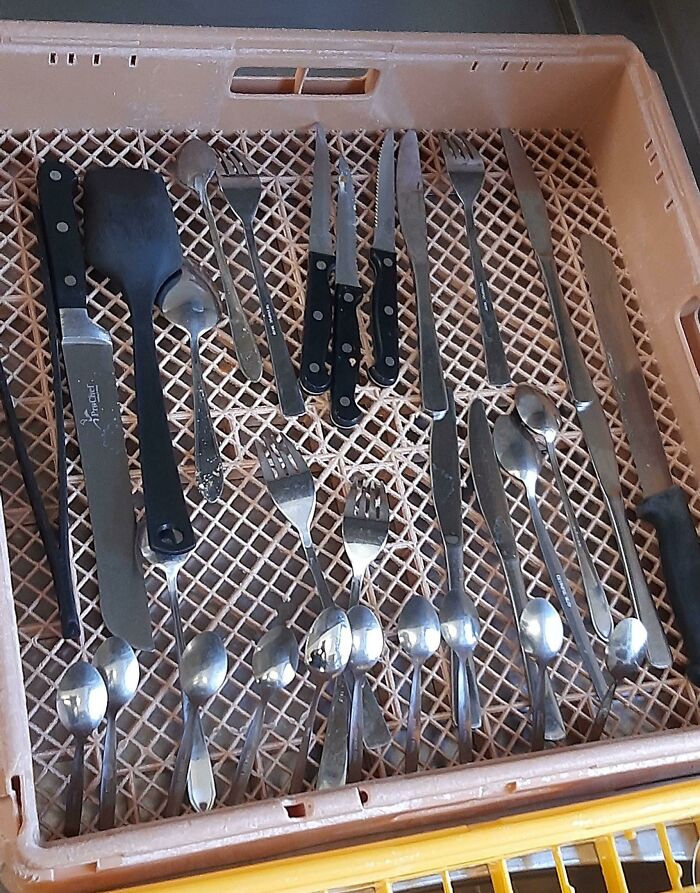 Assorted cutlery and utensils in a drying rack, showcasing tools from the food service industry.