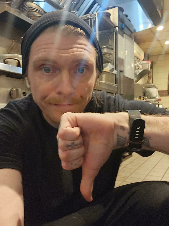 Chef in a kitchen giving a thumbs down, illustrating a tough day in the food service industry.