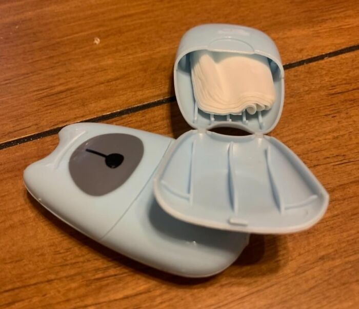 Blue portable case with mini tissues for minimalist carry-on packing on a wooden surface.