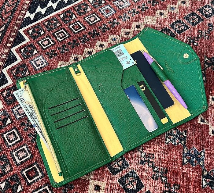 Green travel wallet open with mini items on a patterned rug, ideal for minimalist carry-on packing.