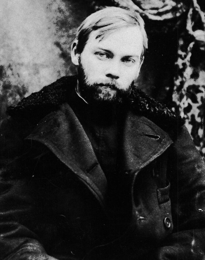 A sepia-toned portrait of an inventor, wearing a heavy coat, with a somber expression.