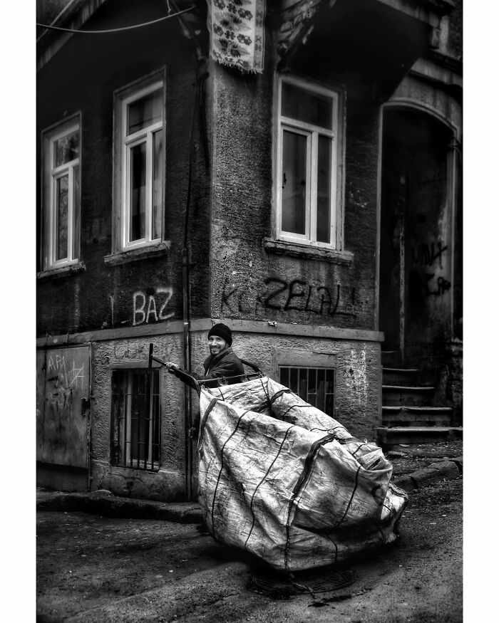 Person with a cart in front of an old building, showcasing rural Turkey in a stunning black-and-white photograph.