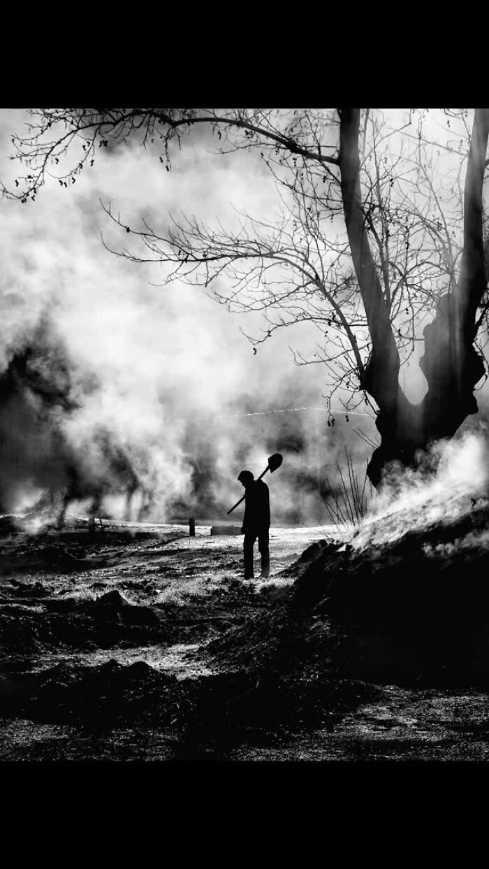Black-and-white image of a person with a shovel, surrounded by misty countryside, capturing rural Turkey's essence.