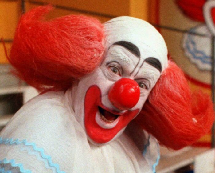 Clown with bright red hair and nose smiling in a nostalgic moment from people realizing they’re old now.