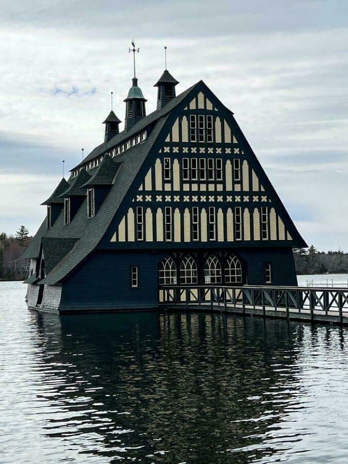 Unique architectural feat of a large Tudor-style building rising from the water with a connected wooden walkway.