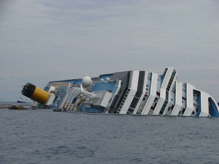 Capsized cruise ship resting on its side near the shoreline, illustrating fascinating world facts.