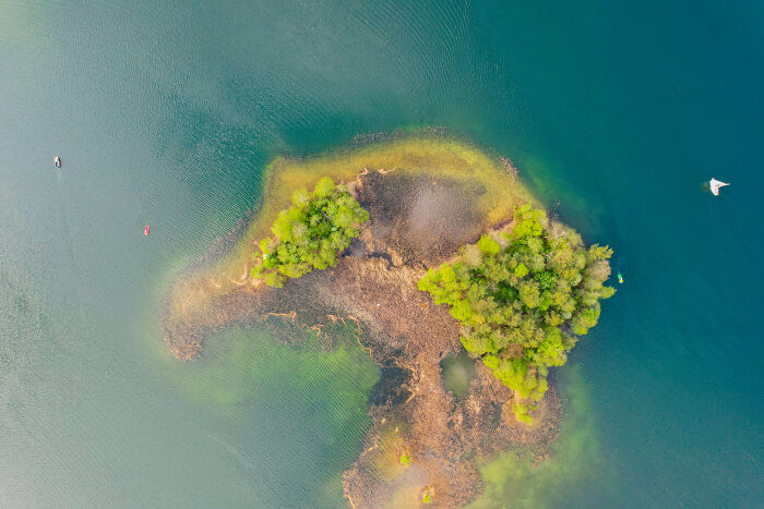 Aerial view of an island with lush greenery surrounded by water in Lithuania.