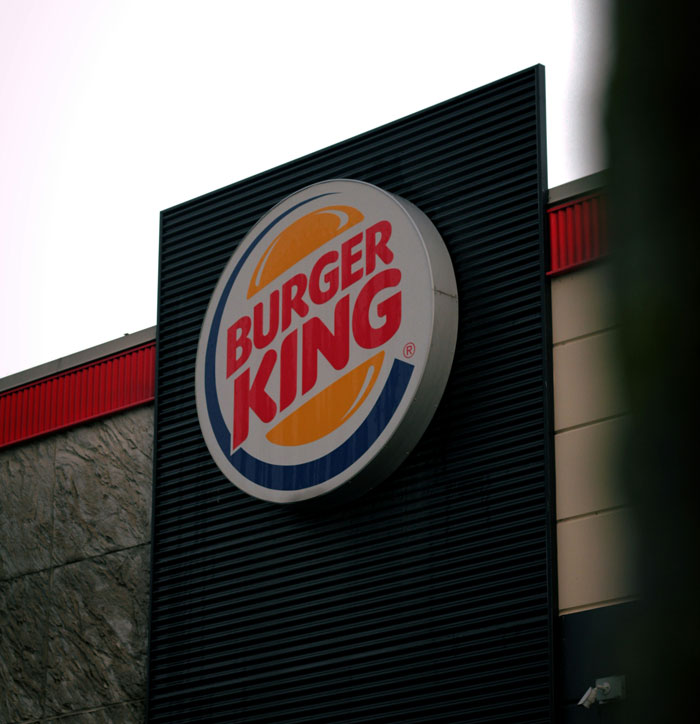 Burger King sign on a building under a cloudy sky.