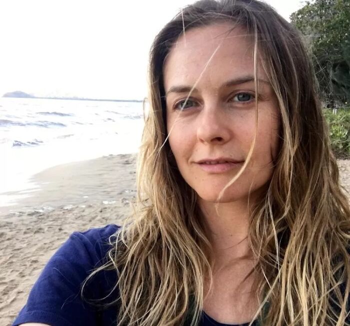 Actress on a beach without makeup, showcasing natural beauty.