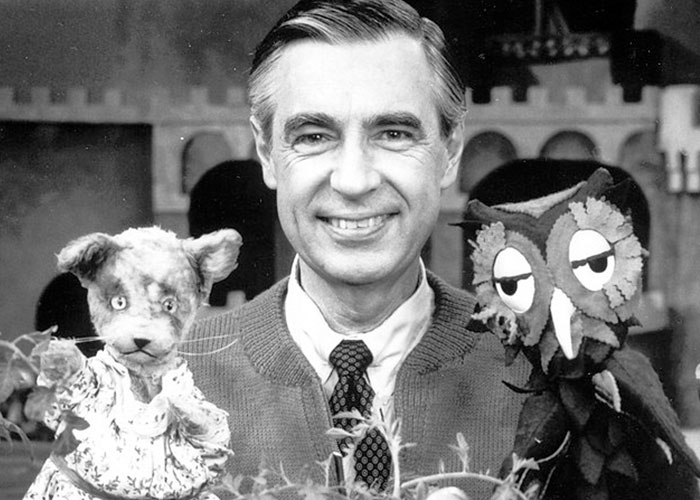 A smiling man with wholesome puppets in a friendly setting.