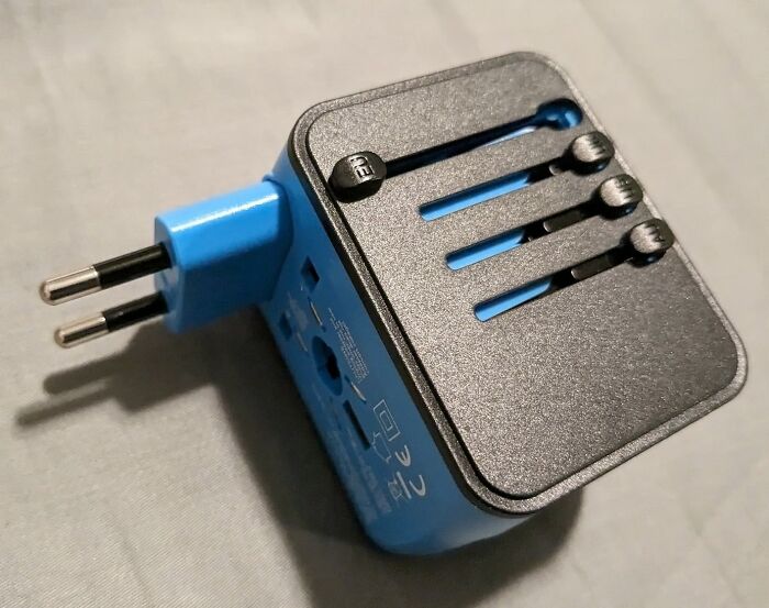 A blue universal travel adapter with European plug, essential for avoiding common travel mistakes.