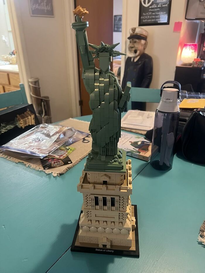 LEGO Statue of Liberty on a teal table, surrounded by various items, illustrating a successful impulse buy.