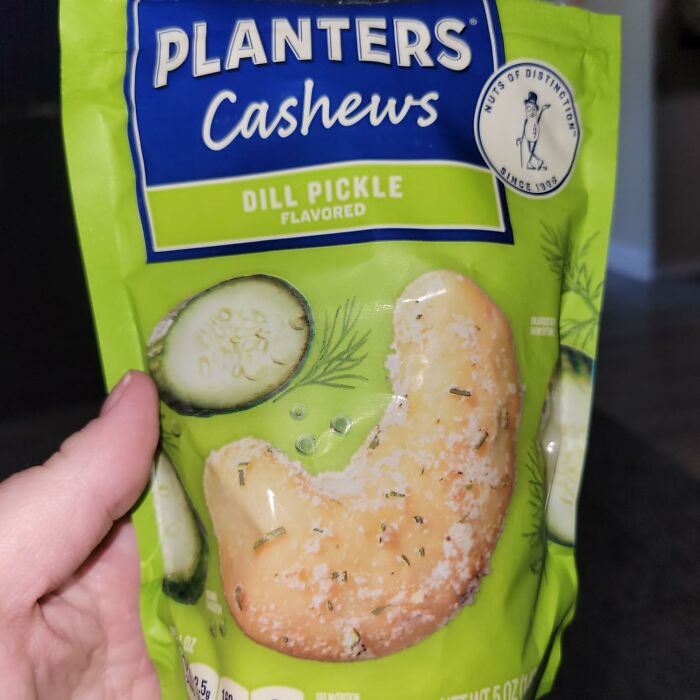 Planters Dill Pickle cashews package held in hand. Unique snack flavor.