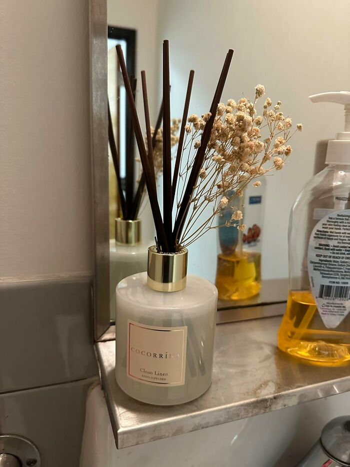 Luxury reed diffuser with dried flowers on bathroom shelf, showcasing expensive taste on a humble budget.