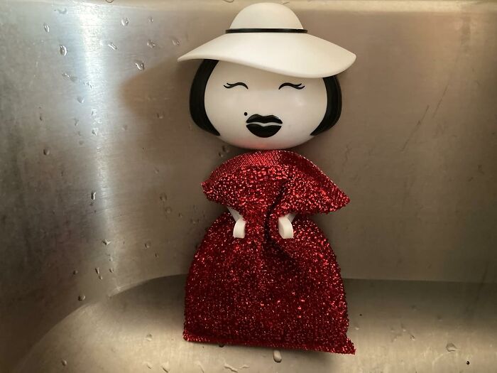 A figurine in a red glittery dress with a white hat, part of a collection of random things that catch attention.