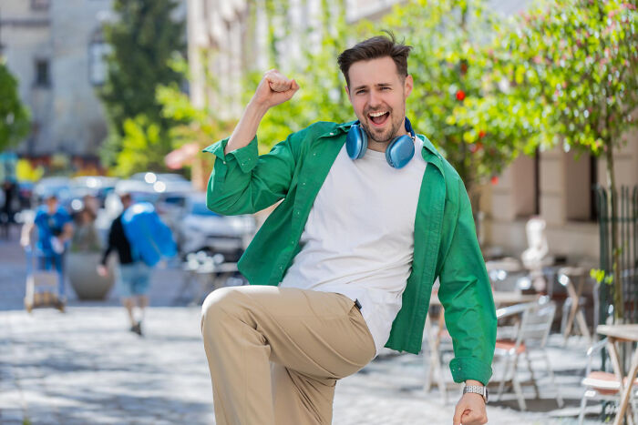 A joyful man with headphones in an urban setting, symbolizing USA lifestyle elements that may confuse foreigners.
