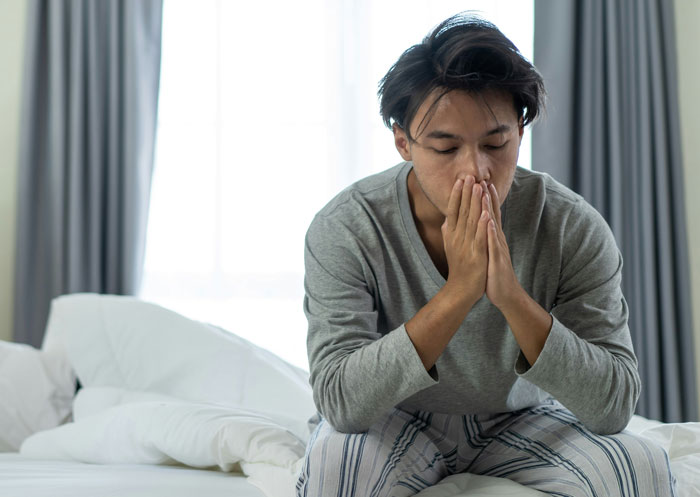 Man sitting on a bed looking distressed, contemplating his marriage over. Man sitting on a bed looking distressed, contemplating his marriage over.