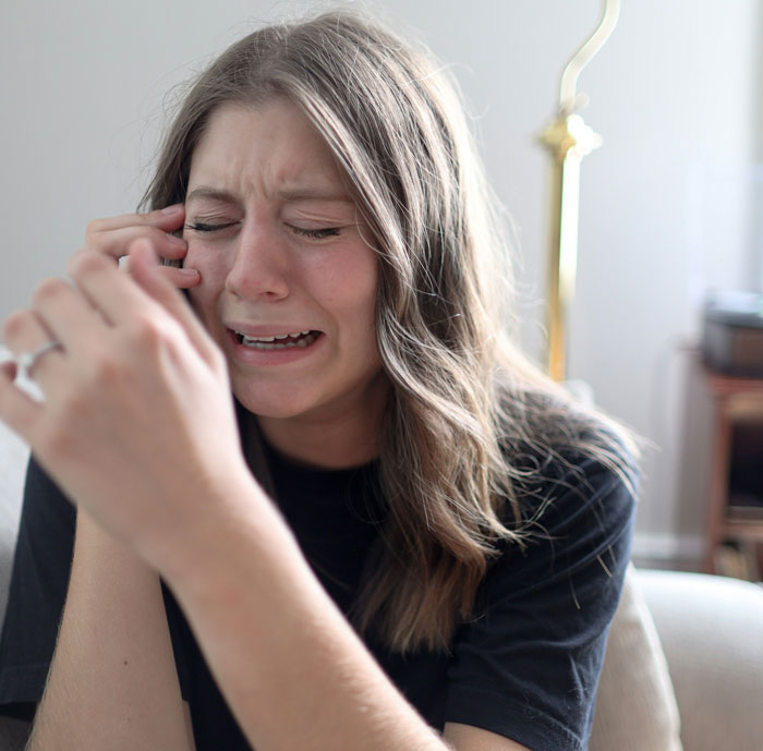 A woman crying while on the phone, reflecting emotional impact of uncovering a man's background.