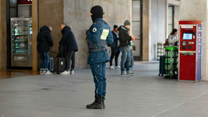 Security guard on duty in a public area, monitoring surroundings, highlighting professions often needed for safety.