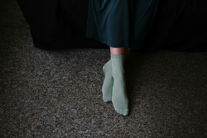 Person wearing green socks sitting on carpet, illustrating deeply weird habits concept.