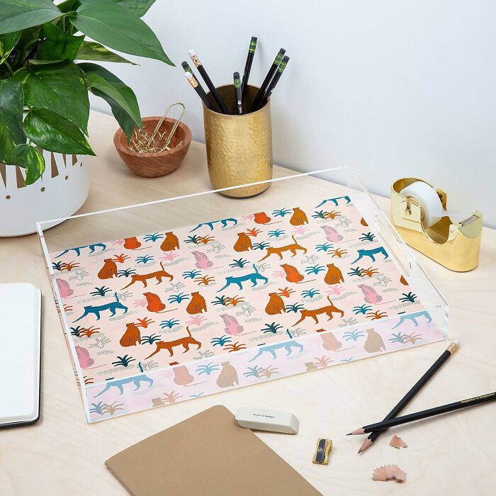 Decorative desk setup featuring Society 6 art tray, pencils, a plant, and office supplies.