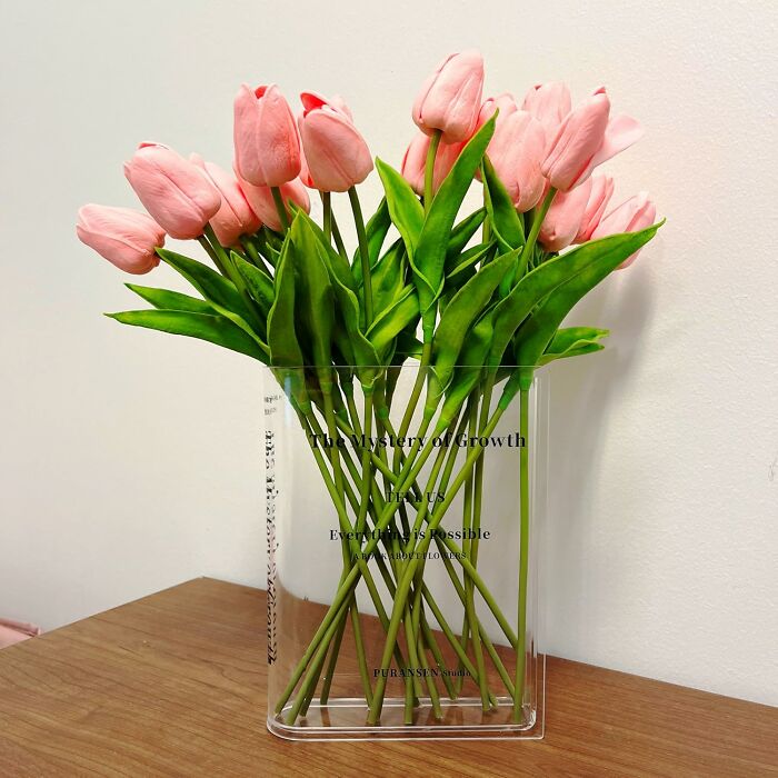 Pink tulips in a clear stylish vase on a wooden surface, blending utility and aesthetics.