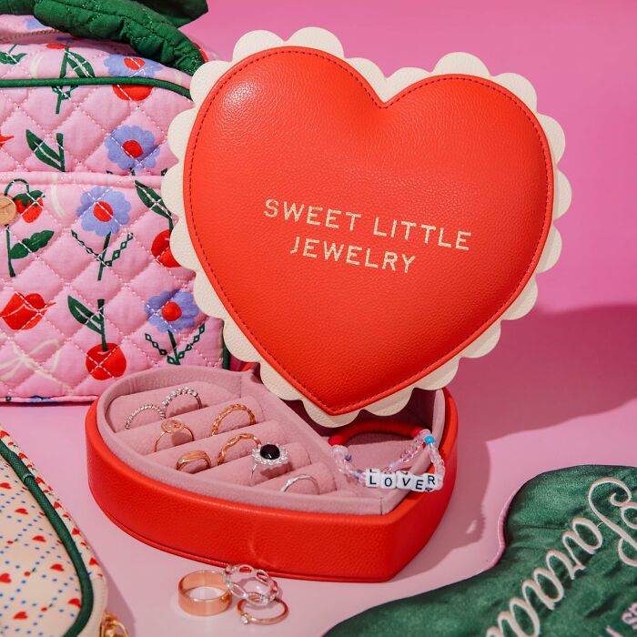 Heart-shaped jewelry case from Bando, open to show rings and a bracelet against a pink floral background.