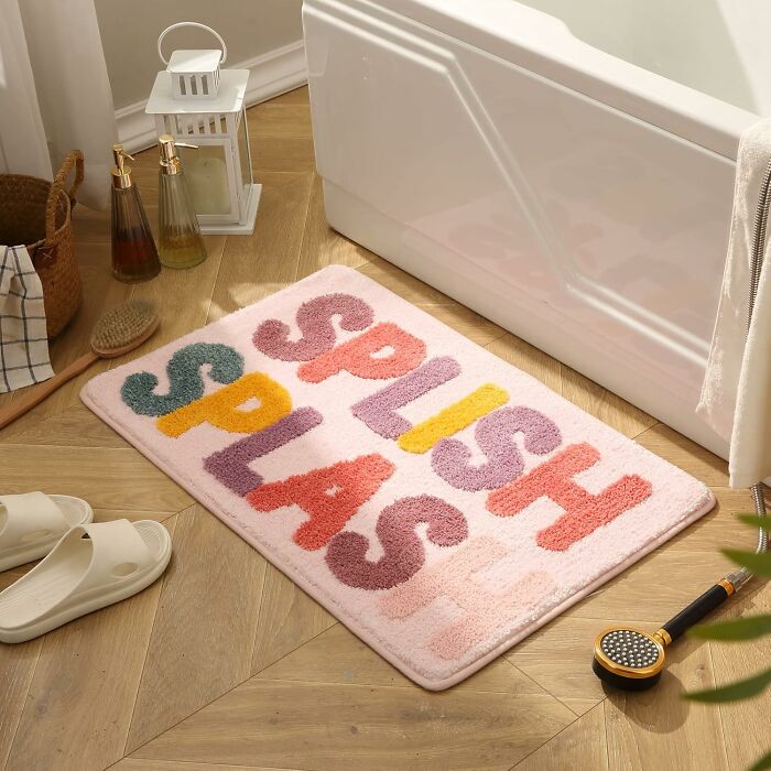 Colorful bathroom mat on wooden floor next to bathtub, featuring bold letters, perfect for upgrading bathroom mats that actually slay.