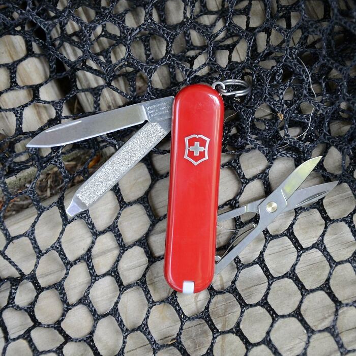Red Swiss Army Knife with various tools on a net background, representing items worth every cent.