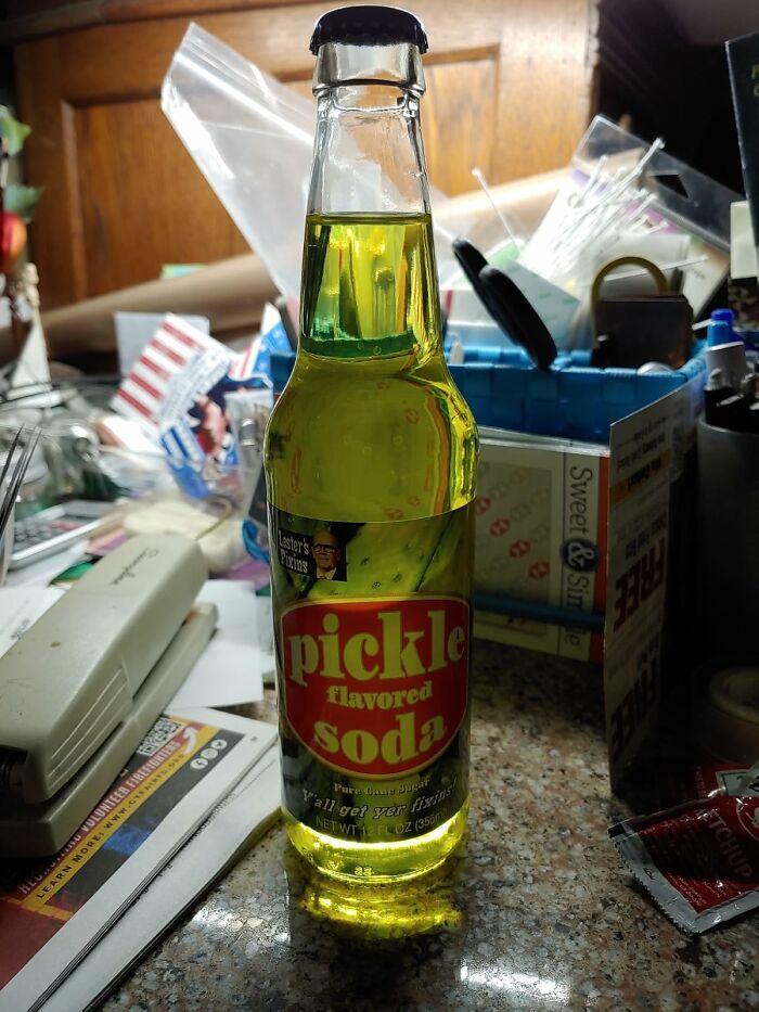Pickle-flavored soda bottle on a cluttered kitchen counter.