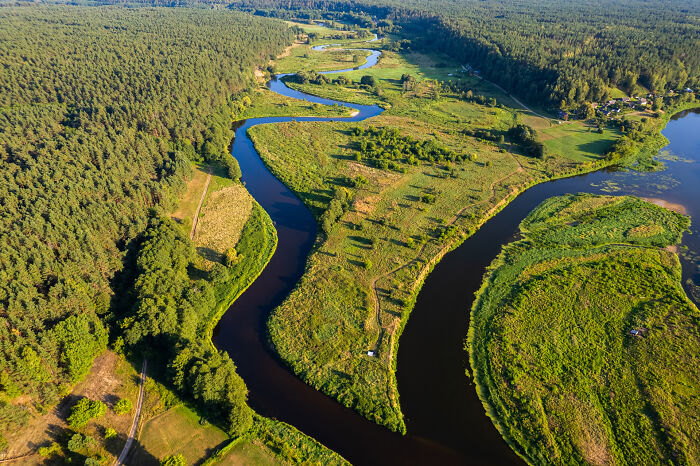 Aerial view of Lithuania's lush green landscape with winding river, showcasing beautiful scenery from above.