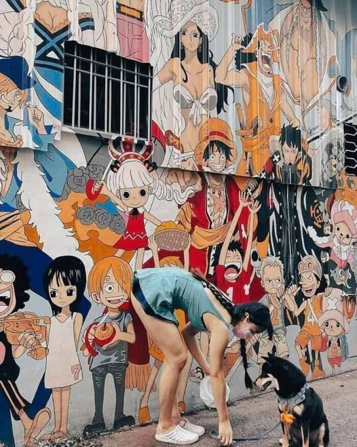 Mujer con perro frente a mural de personajes de anime, un ejemplo de imágenes raras y llamativas para ver.