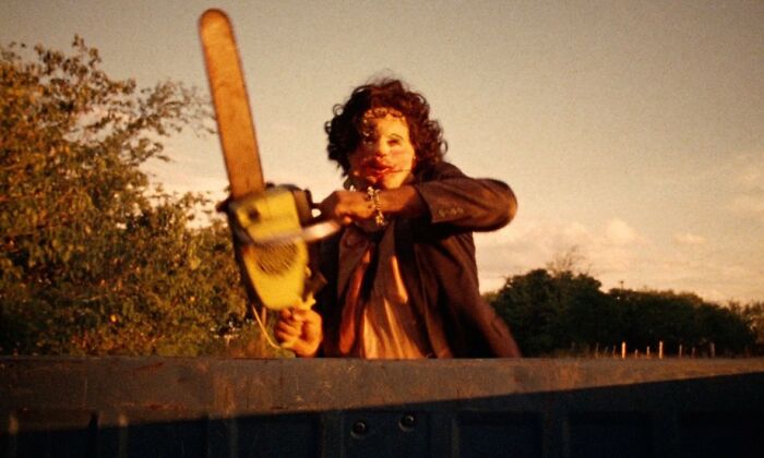 Character holding a chainsaw, iconic movie prop, in an outdoor setting during sunset.