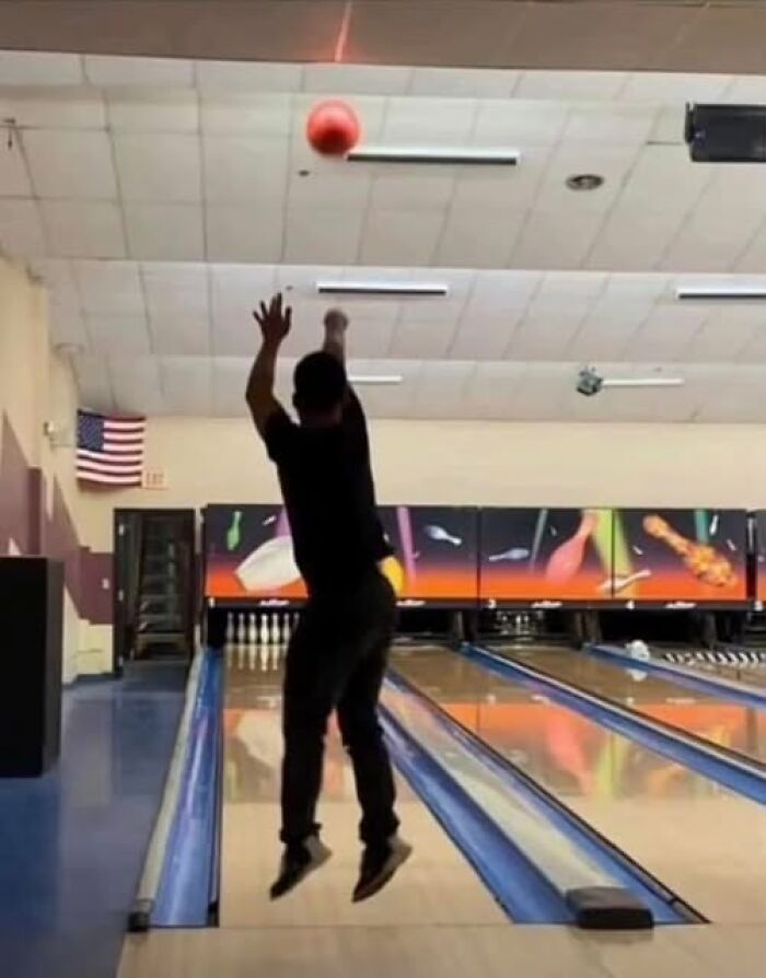 Person jumps while releasing a bowling ball at a bowling alley, illustrating a weird image worth seeing.