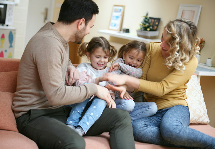 A family with two children playing on a couch, capturing a happy moment despite marital issues. A family with two children playing on a couch, capturing a happy moment despite marital issues.