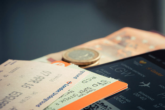 Travel documents and currency next to a smartphone, suggesting ideas for a safe side hustle.