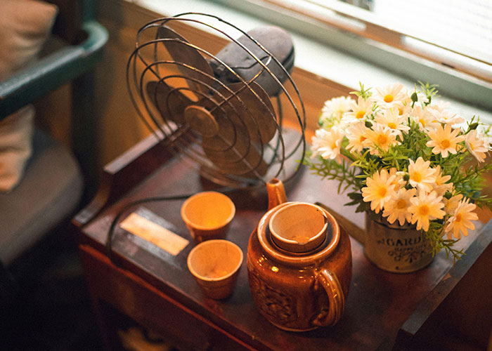 Vintage fan and pottery alongside flowers, reflecting European nostalgia.