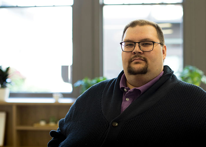 A person wearing glasses and a sweater, sitting indoors, highlighting challenges of being overweight.