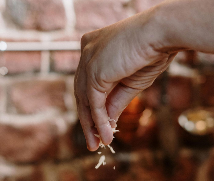 Hand sprinkling cheese over a dish, representing hilarious classroom moments shared by teachers.