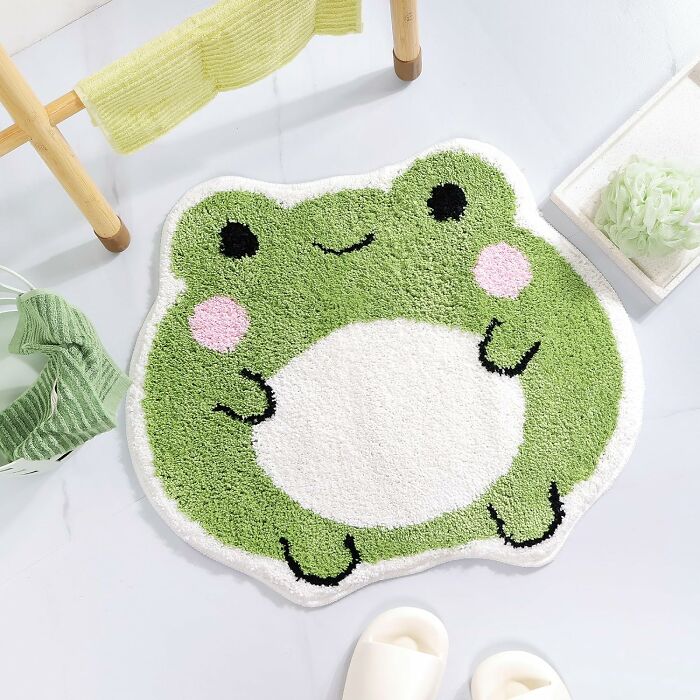 Green frog-shaped bathroom mat with soft texture placed on white floor, enhancing bathroom mats decor and comfort.