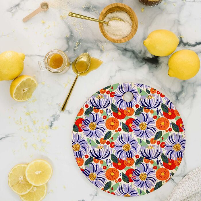 Floral designed cutting board with lemons and kitchenware on marble surface from Society 6.
