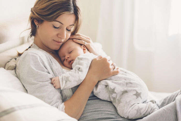 Mother holding a sleeping baby in a cozy setting, highlighting family care in the context of USA healthcare discussions.