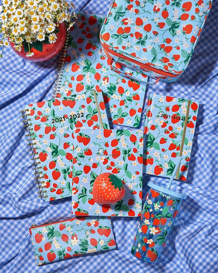Bando stationery and accessories with colorful strawberry patterns on a checkered blue cloth.