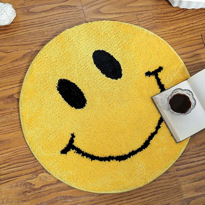 Round yellow bathroom mat with a smiley face design on wood floor, enhancing bathroom decor and style.